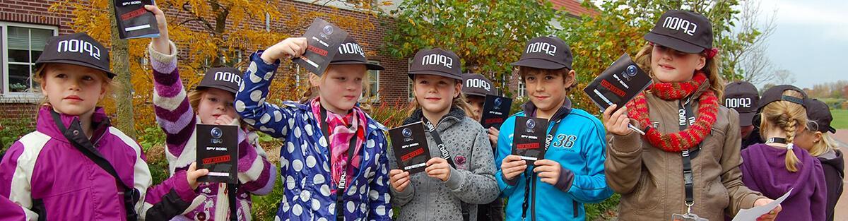 Kinderen laten tijdens het spel op school hun spionnen handboek zien